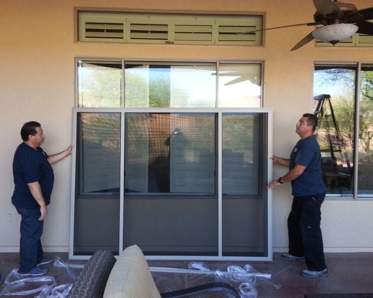 Two men are working on a screen door.