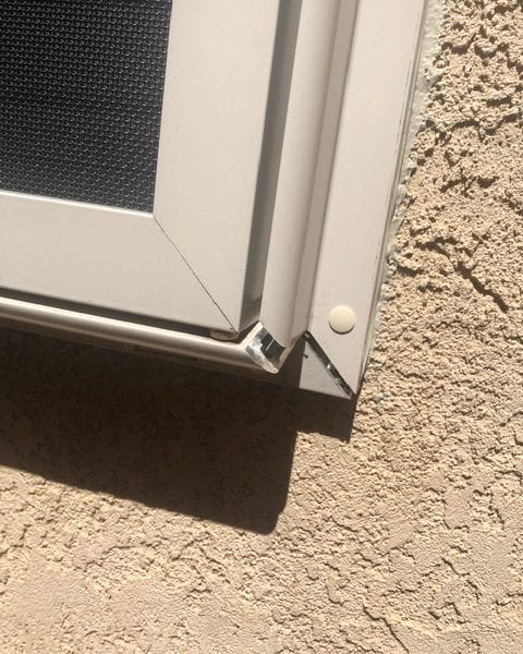 A white window with a metal grill on the outside.