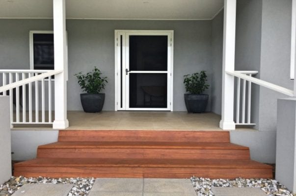 A porch with steps and plants on the ground.