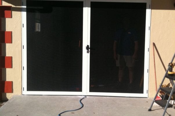 A man standing in front of a sliding glass door.
