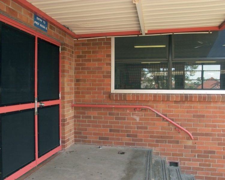 A red door and window in an enclosed area.