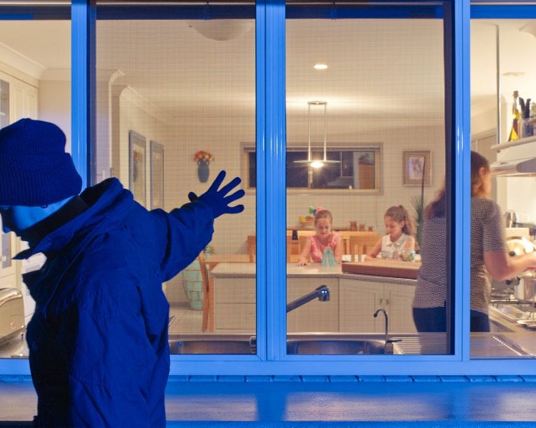 A person standing in front of a window with people sitting at the table.